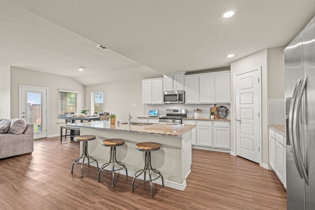 kitchen with white cabinetry, sink, backsplash, a center island with sink, and appliances with stainless steel finishes