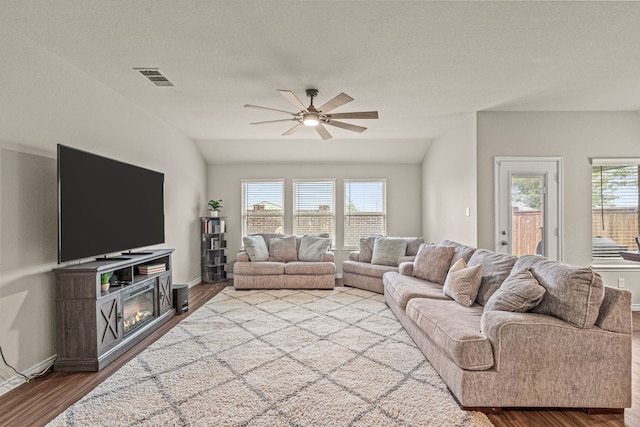 living room with ceiling fan, wood-type flooring, lofted ceiling, and a textured ceiling