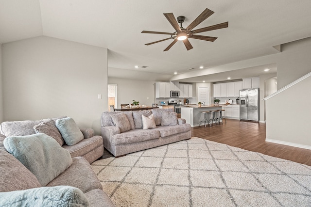 living room featuring ceiling fan, light wood-type flooring, and vaulted ceiling