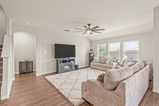 living room with hardwood / wood-style flooring, ceiling fan, lofted ceiling, and a fireplace