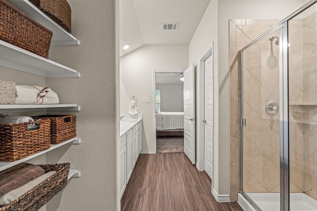 bathroom featuring ceiling fan, wood-type flooring, vaulted ceiling, vanity, and a shower with shower door