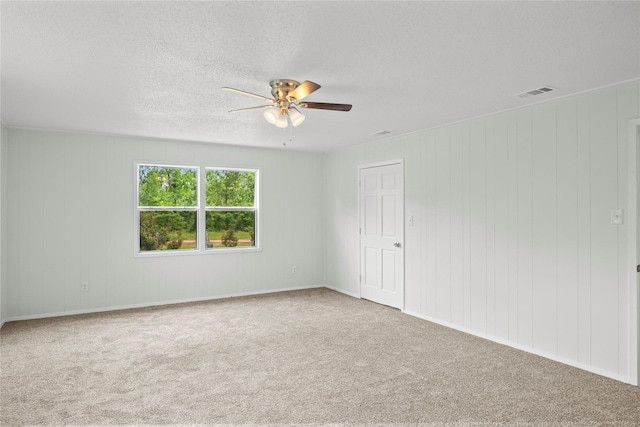 carpeted spare room with ceiling fan and wooden walls