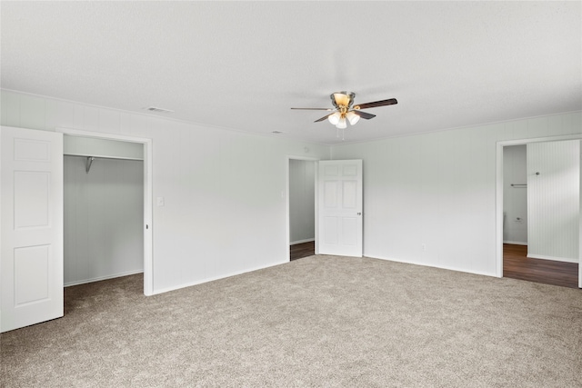 unfurnished bedroom with a closet, dark carpet, and ceiling fan