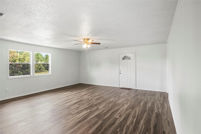 unfurnished room featuring hardwood / wood-style floors, ceiling fan, a textured ceiling, and wooden walls