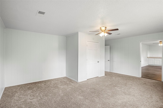 empty room with carpet flooring, ceiling fan, and a textured ceiling