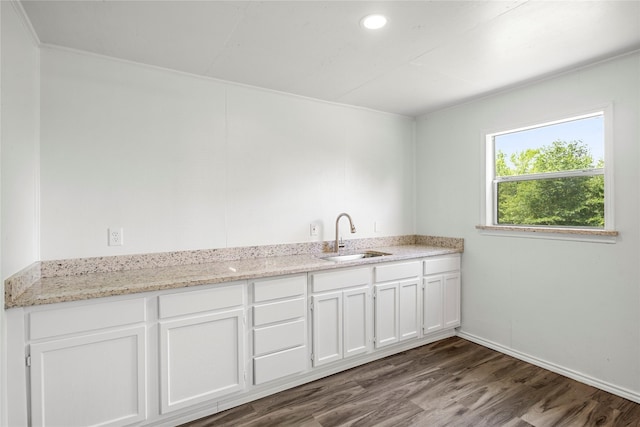 kitchen with light stone countertops, white cabinetry, sink, and dark wood-type flooring