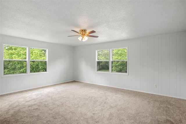 carpeted spare room with plenty of natural light and ceiling fan