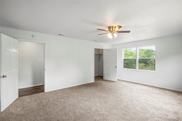 unfurnished bedroom with a textured ceiling, dark carpet, and ceiling fan