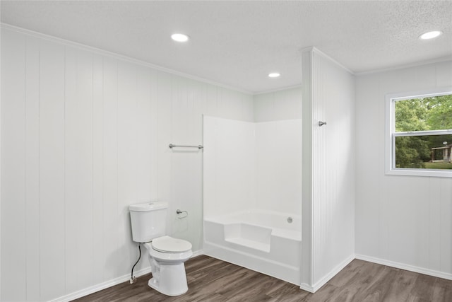 bathroom featuring hardwood / wood-style floors, toilet, crown molding, and a tub