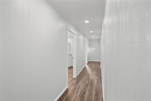 hallway with wood-type flooring and ornamental molding