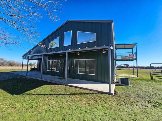 back of property with a lawn, cooling unit, and a patio area