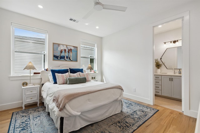 bedroom with ensuite bathroom, ceiling fan, light hardwood / wood-style floors, and sink