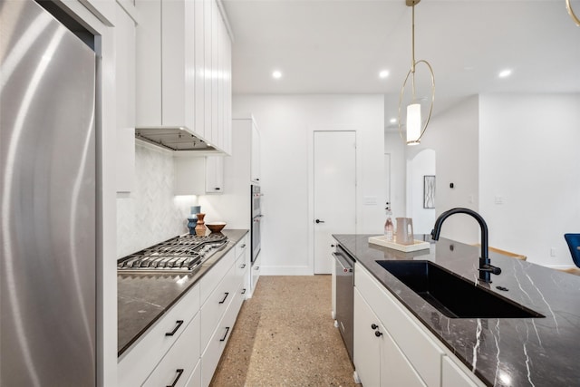 kitchen with white cabinets, sink, hanging light fixtures, dark stone countertops, and appliances with stainless steel finishes