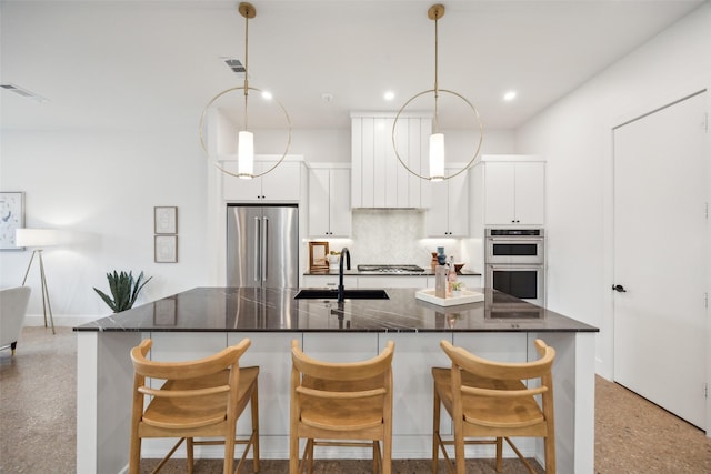 kitchen with a kitchen breakfast bar, stainless steel appliances, sink, decorative light fixtures, and white cabinetry