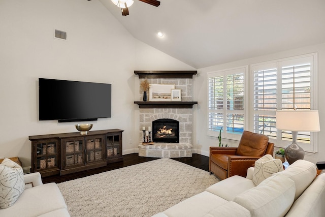 living room featuring hardwood / wood-style flooring, a stone fireplace, high vaulted ceiling, and ceiling fan