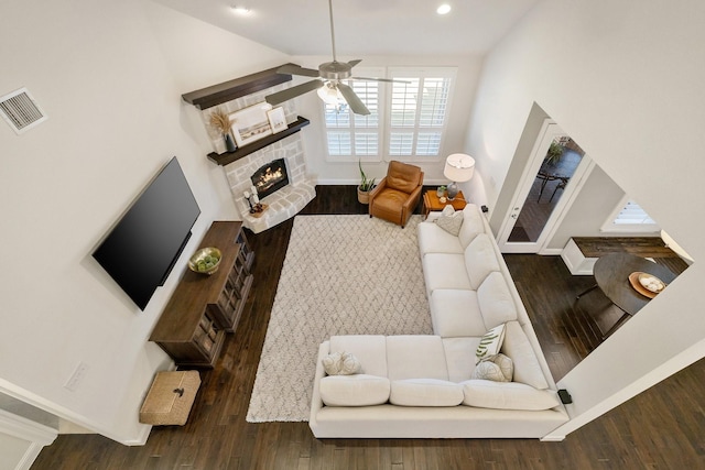 living room featuring dark hardwood / wood-style flooring, a brick fireplace, and ceiling fan