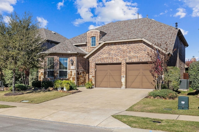 view of front facade featuring cooling unit, a garage, and a front yard