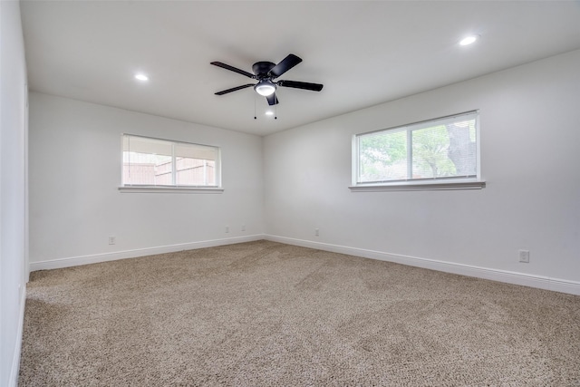 carpeted spare room featuring plenty of natural light and ceiling fan