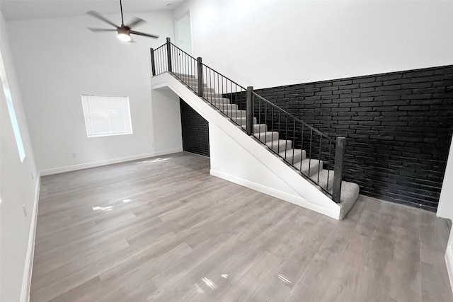 staircase featuring ceiling fan, wood-type flooring, and a towering ceiling