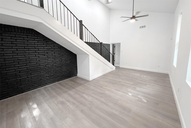 interior space featuring brick wall, a high ceiling, and light hardwood / wood-style floors