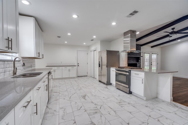 kitchen featuring sink, wall chimney exhaust hood, tasteful backsplash, white cabinets, and appliances with stainless steel finishes