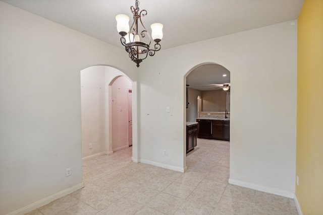 tiled spare room with sink and ceiling fan with notable chandelier