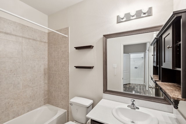 full bathroom with vanity, tiled shower / bath, and toilet