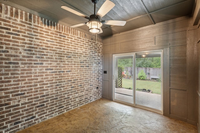 doorway with ceiling fan and brick wall