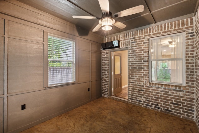 spare room with ceiling fan and brick wall