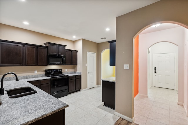 kitchen featuring dark brown cabinetry, sink, black appliances, and light stone countertops