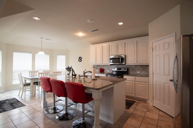 kitchen featuring stainless steel appliances, a kitchen island with sink, sink, white cabinetry, and hanging light fixtures