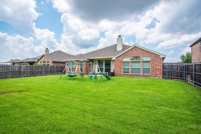 back of house with a playground and a yard