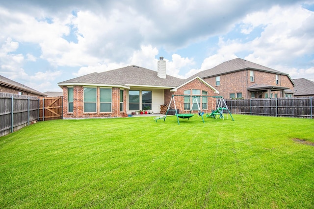 back of property with a yard and a playground