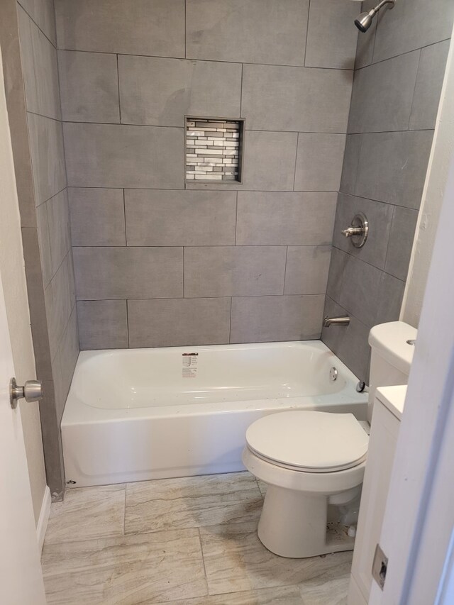 full bathroom featuring tiled shower / bath combo, vanity, and toilet