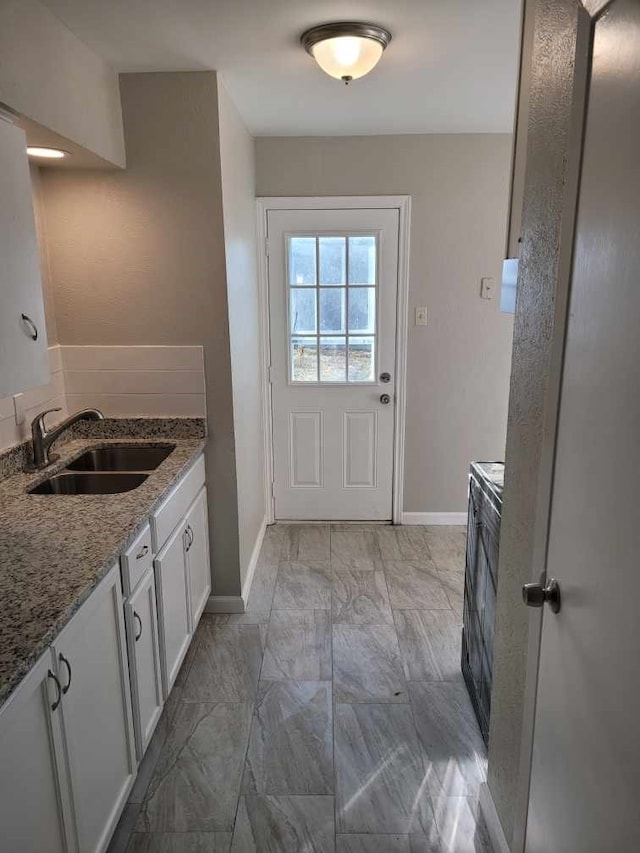 interior space with stone counters, sink, and white cabinets