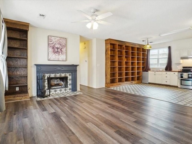 unfurnished living room featuring ceiling fan, built in features, a fireplace, and dark hardwood / wood-style flooring