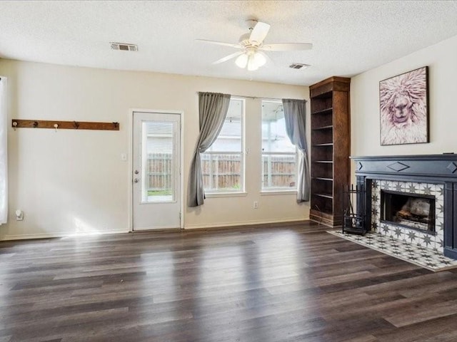 unfurnished living room with ceiling fan, a textured ceiling, dark hardwood / wood-style floors, and a fireplace