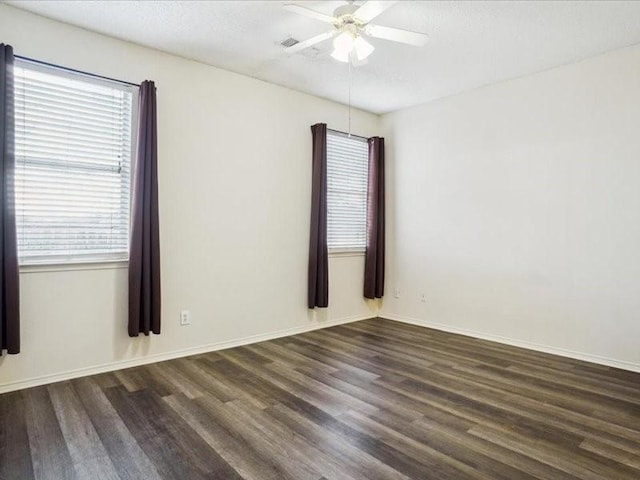 spare room with ceiling fan, dark wood-type flooring, and a wealth of natural light