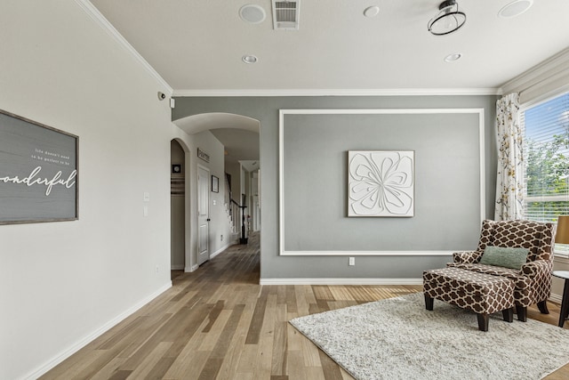 living area featuring wood-type flooring and ornamental molding