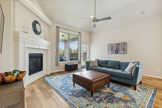 living room with hardwood / wood-style flooring, a brick fireplace, ceiling fan, and lofted ceiling