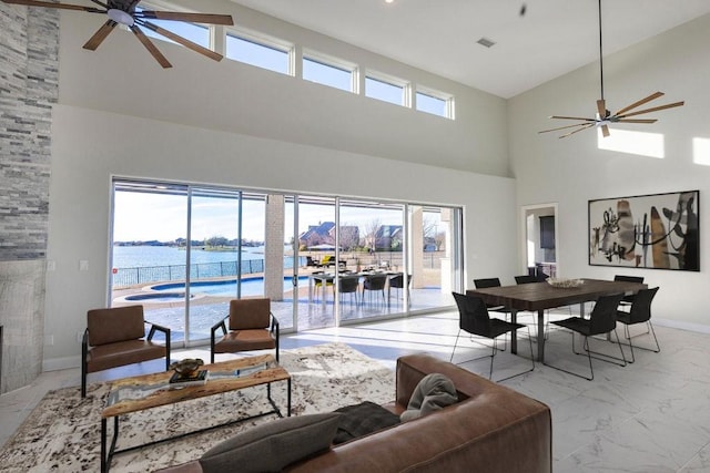 living area featuring marble finish floor, ceiling fan, a stone fireplace, and baseboards