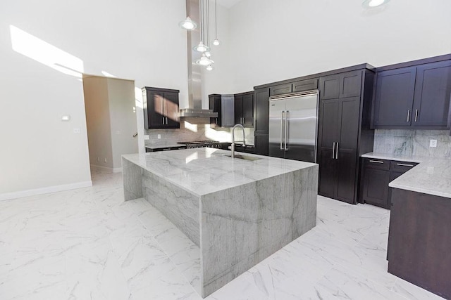 kitchen featuring light stone counters, marble finish floor, stainless steel built in fridge, a sink, and exhaust hood