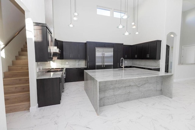 kitchen with marble finish floor, stainless steel appliances, light stone counters, and decorative light fixtures