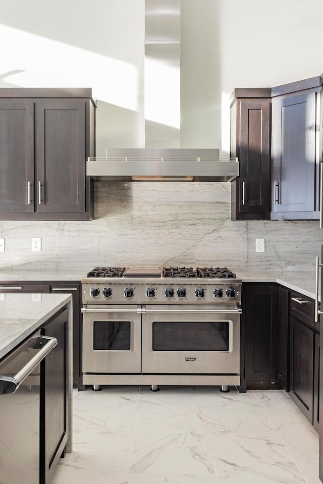 kitchen with marble finish floor, wall chimney exhaust hood, appliances with stainless steel finishes, and backsplash