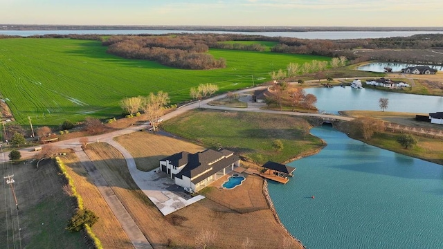 aerial view at dusk featuring a rural view and a water view