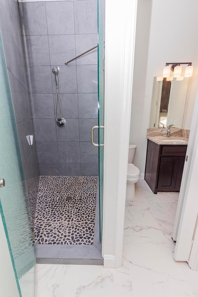 full bathroom featuring marble finish floor, toilet, a stall shower, vanity, and baseboards