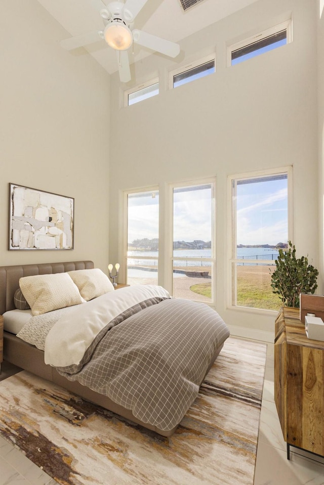 bedroom featuring multiple windows, ceiling fan, visible vents, and a high ceiling