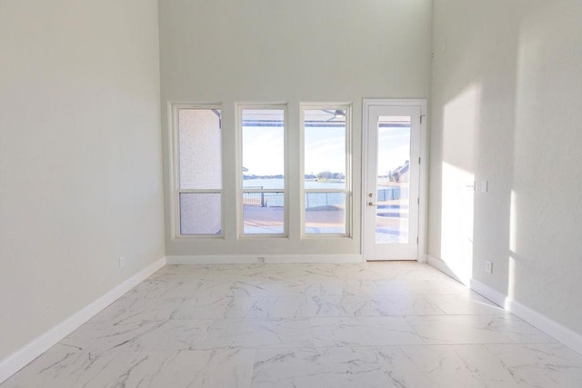 unfurnished room featuring marble finish floor and baseboards