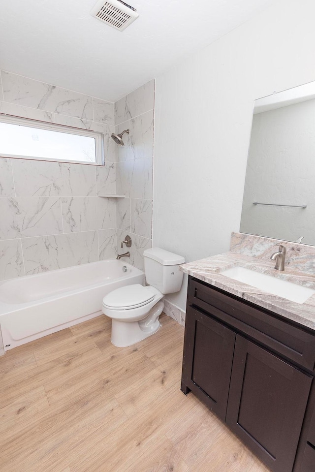 bathroom featuring visible vents, shower / bathing tub combination, toilet, vanity, and wood finished floors