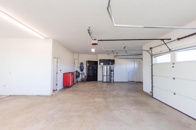 garage with a garage door opener and freestanding refrigerator